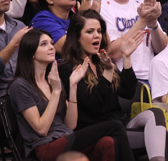 Khloé Kardashian and Kendall Jenner enthusiastically cheer courtside while sporting coordinating paneled denim looks