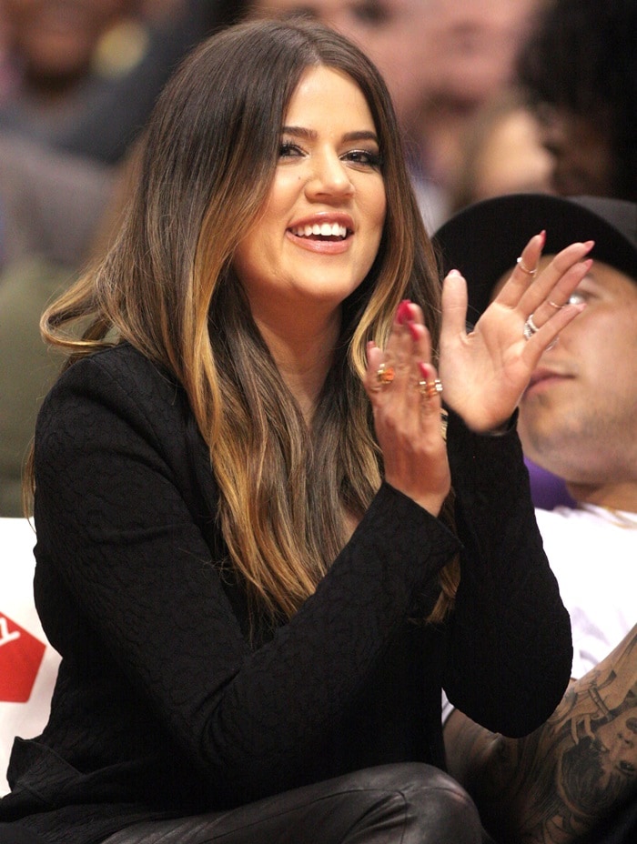 Khloé Kardashian claps courtside while showcasing her ombré hairstyle and a textured black blazer
