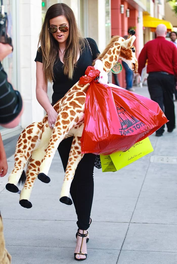 Khloé Kardashian in an all-black ensemble consisting of tight black trousers and a tight v-neck t-shirt