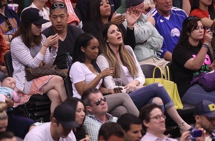 Khloé Kardashian wears a long-sleeved tee, jeans and a vest to an NBA game