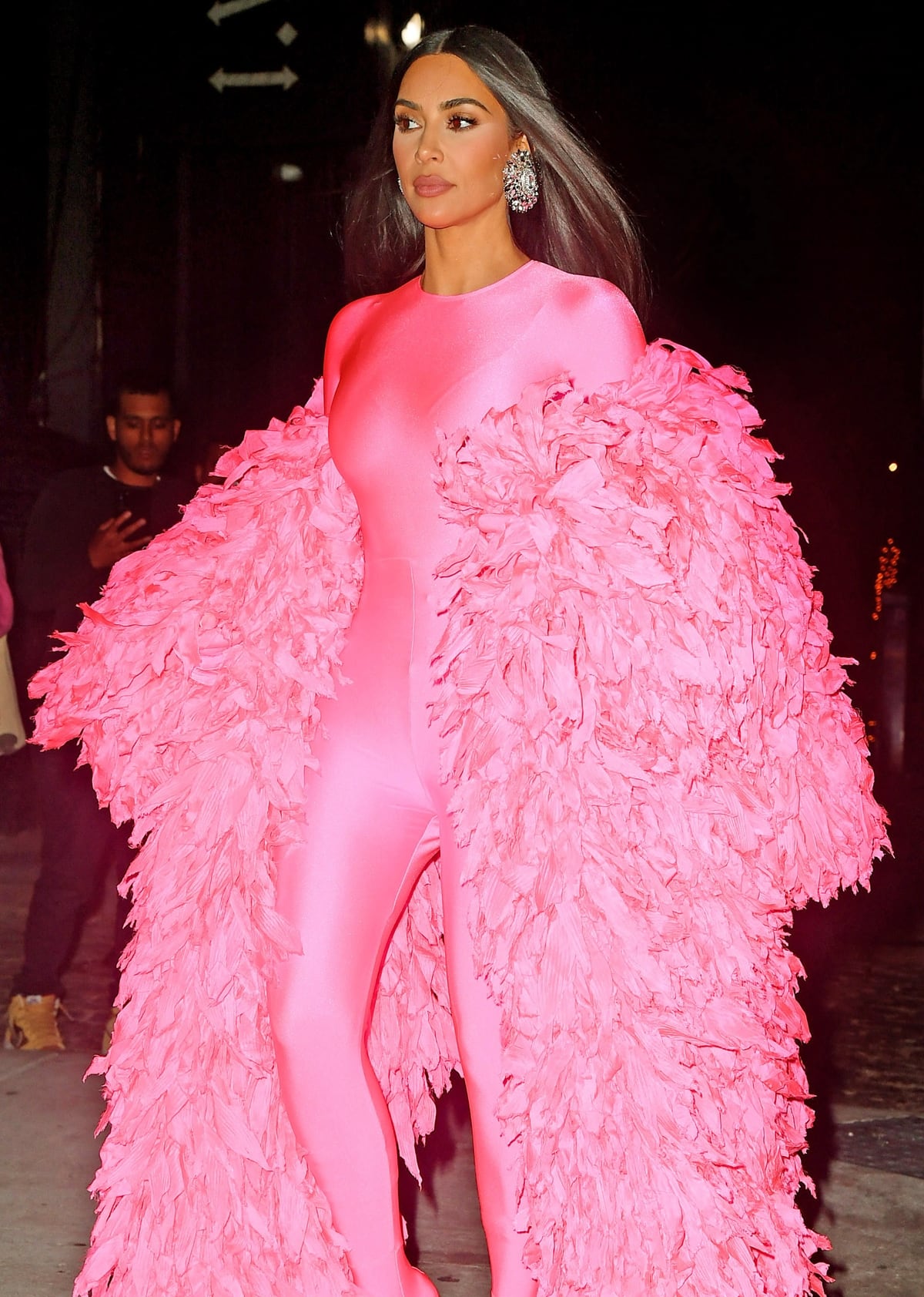 Kim Kardashian arrives at the SNL after-party enveloped in a dramatic feathered Balenciaga coat layered over a glossy, bubblegum-pink catsuit