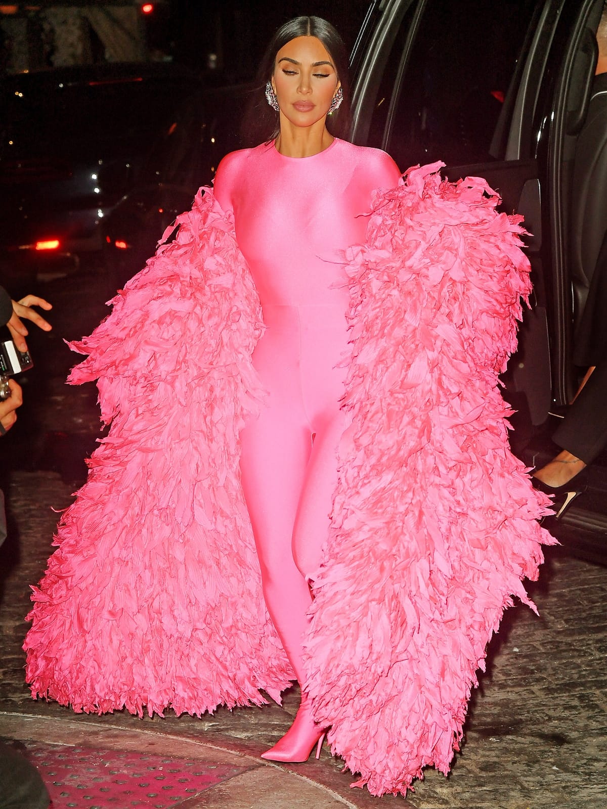 Kim Kardashian heads to the SNL after-party in New York City wearing a head-to-toe Balenciaga look, pairing a crushed-velvet turtleneck jumpsuit with matching stretch-velvet Knife boots and dramatic feathered coat