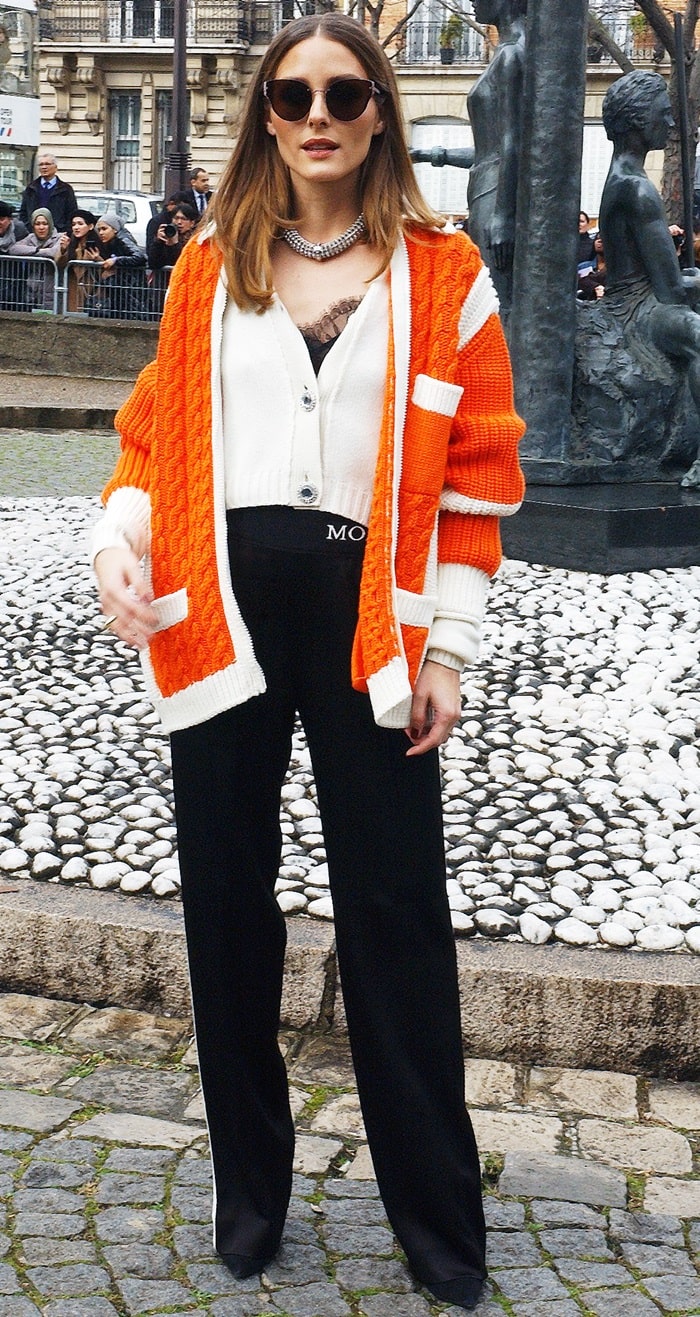 Olivia Palermo stuns at the Miu Miu show in Paris, pairing a chic Miu Miu wool cardigan with Moncler track pants and her signature Westward Leaning x Olivia Palermo Bristol sunglasses for a casually polished look