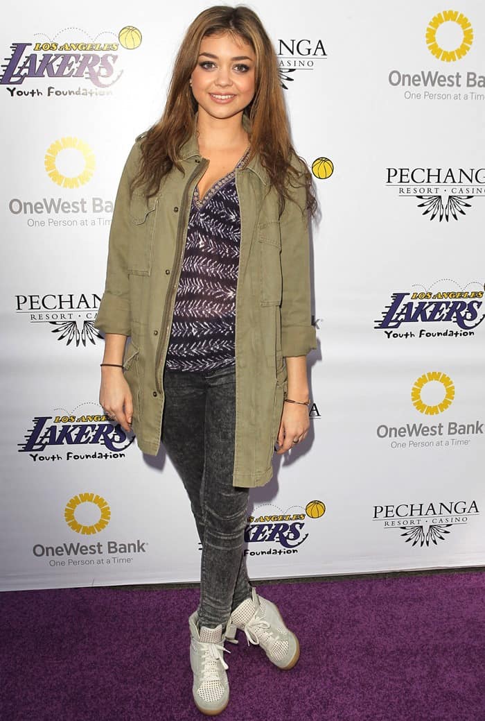 Sarah Hyland effortlessly nails sporty-chic by pairing her perforated sneaker wedges with acid-wash skinny jeans, a patterned top, and an olive utility jacket for a laid-back yet stylish look