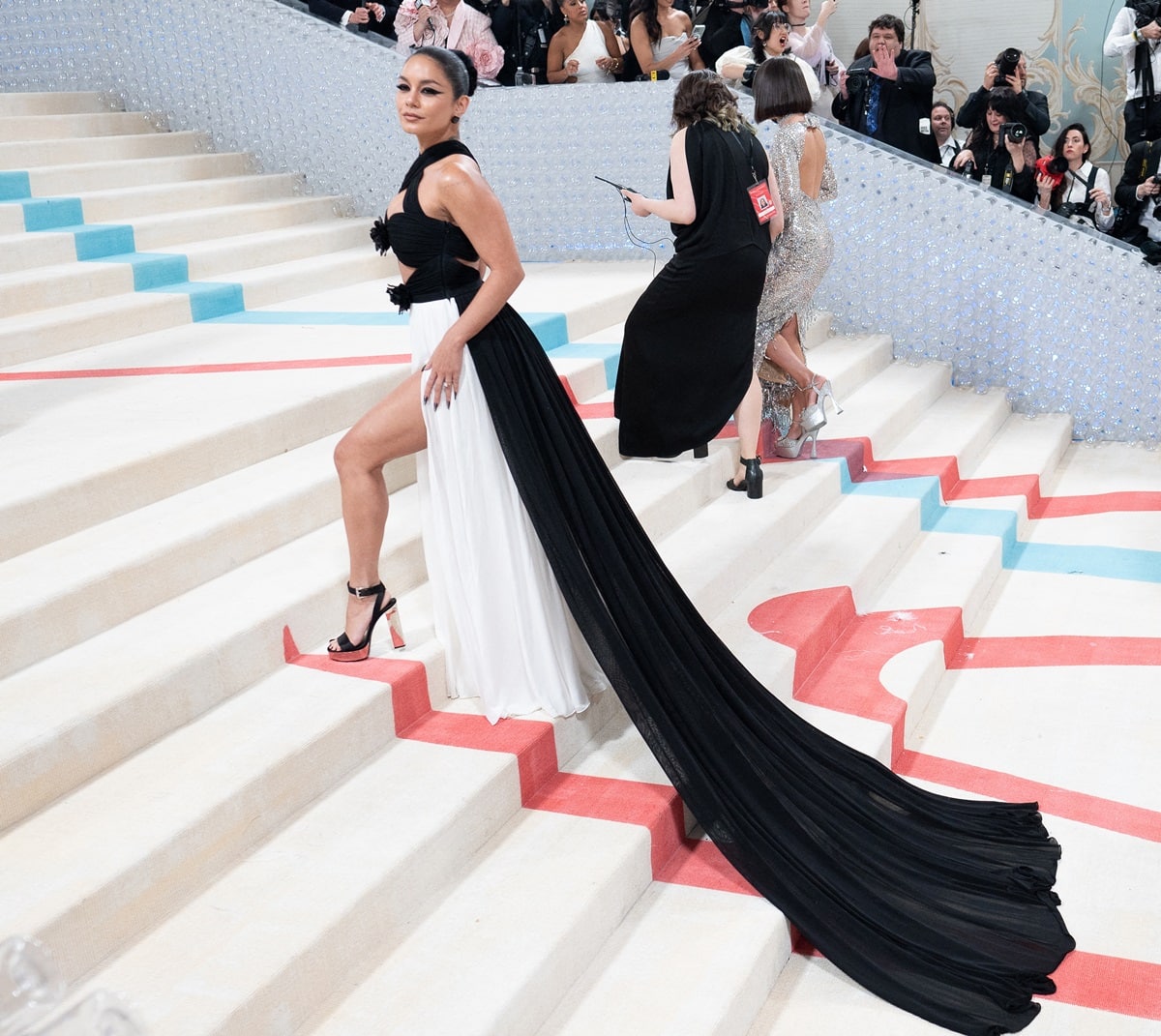 Vanessa Hudgens made a striking entrance at the 2023 Costume Institute Benefit celebrating Karl Lagerfeld: A Line of Beauty, commanding the Met steps in her black-and-white Michael Kors gown—its dramatic slit perfectly showcasing her glossy black platform sandals that added height, power, and a sculptural finish to the look
