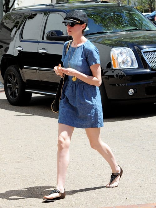 Anne Hathaway keeps her off-duty look relaxed in a softly ruched chambray Madewell dress, styled with embellished flat sandals, a textured newsboy cap, and dark sunglasses while running errands in Beverly Hills