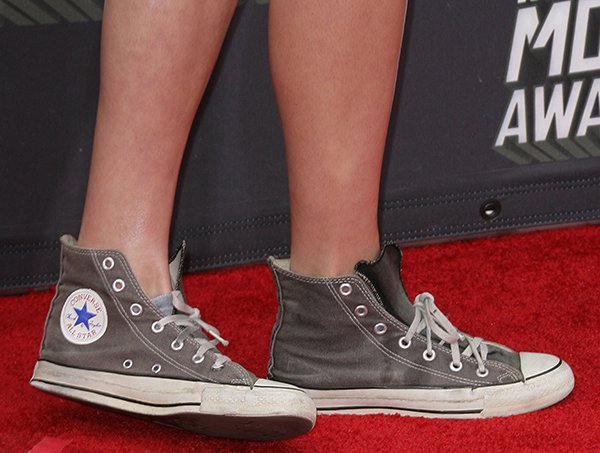 Opting for comfort over convention, she makes a daring style statement with well-worn gray Converse Chuck Taylor sneakers, adding a casual-cool edge to her ensemble