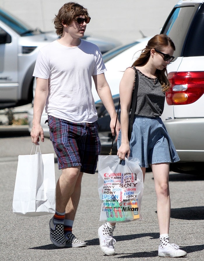 Emma Roberts kept it casual yet chic in a denim skater skirt, studded tank top, and classic white Superga sneakers, while Evan Peters matched her laid-back vibe in plaid shorts, a white tee, and checkerboard Vans slip-ons
