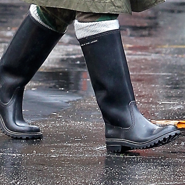 A close-up captures Gwen Stefani’s black knee-high rain boots splashing through rain-soaked streets in Sherman Oaks