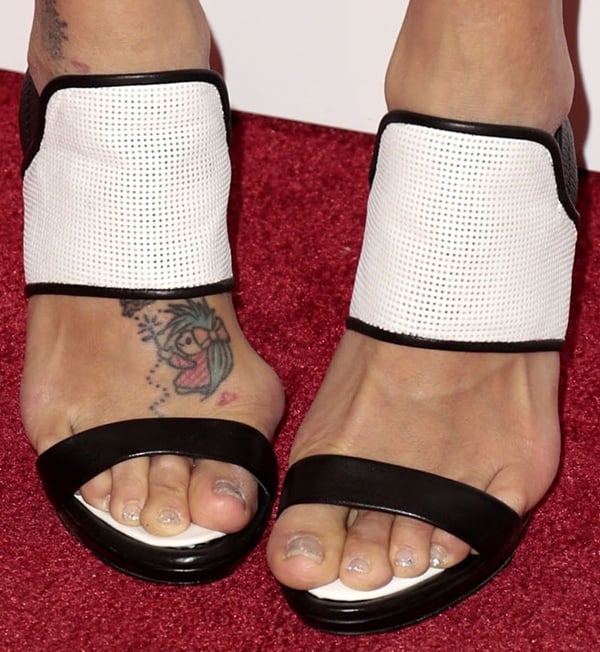 Jeannie Mai showed off her feet in BCBGMAXAZRIA “Jovian” sandals, revealing a colorful cartoon-style tattoo on her right foot and a subtle glittery pedicure that added a playful touch to her sporty-chic look