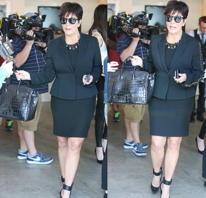 Kris Jenner keeps it sleek in a tailored black suit with chain-detail sleeves, finishing the look with ankle-cuff YSL pumps that add edge and polish to her classic mom-ager style