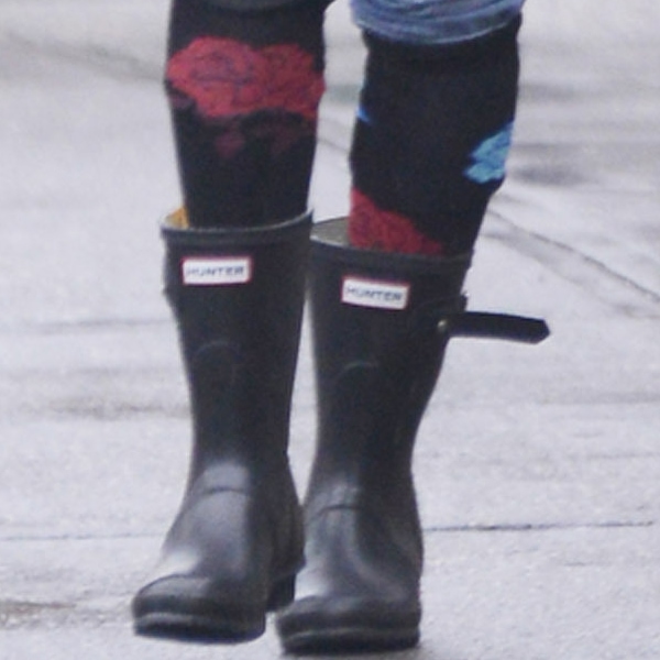 A close-up highlights Sarah Jessica Parker’s black Hunter Original Short Wellies, styled with colorful floral knee socks peeking out for a playful twist on classic rainy-day footwear