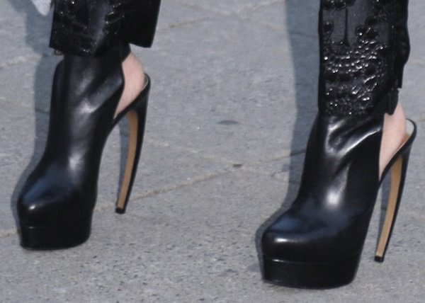 A closer look at Vera Wang’s black platform ankle booties, featuring a rounded toe, elevated platform, and slender stiletto heel that underscore the look’s sharp, fashion-forward edge