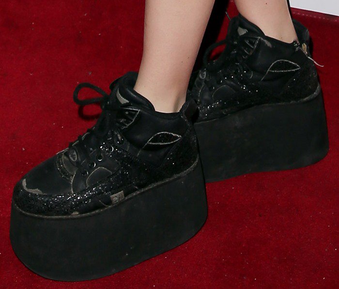 A close-up of Charli XCX’s Buffalo Classic sneakers highlights the massive platform soles, black lace-up uppers, and glittering details that defined her 2013 footwear statement