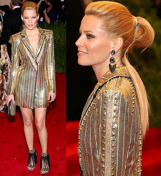 Elizabeth Banks turns heads at the 2013 Met Gala in a shimmering gold chainmail jacket dress by Atelier Versace, paired with fringe-detailed black heels that added a punk-inspired edge to her dazzling look
