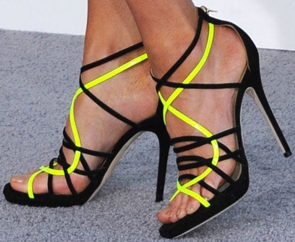 Kate Beckinsale’s Jimmy Choo “Myth” sandals stood out with interlaced black suede straps accented by bold neon yellow detailing