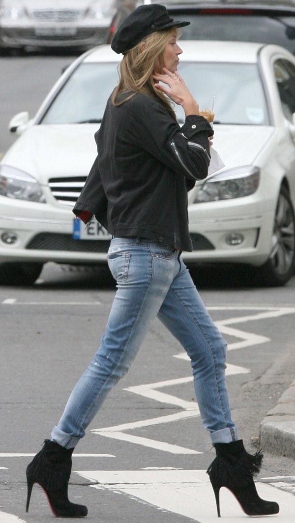 Kate Moss in cuffed and faded jeans, a black zipper-detailed jacket, and a black newsboy cap