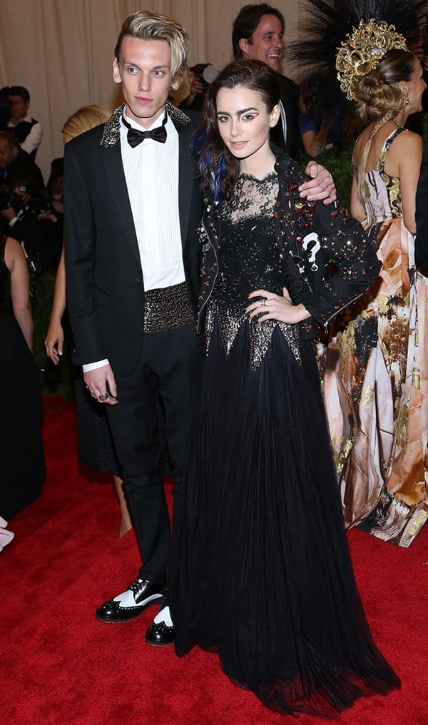 Lily Collins arrives at the PUNK: Chaos to Couture Costume Institute Gala at The Metropolitan Museum of Art on May 6, 2013 Posing with her boyfriend, Jamie Campbell Bower, Lily Collins embraces her punk side in a black Moschino gown adorned with vintage accents at the Met Gala