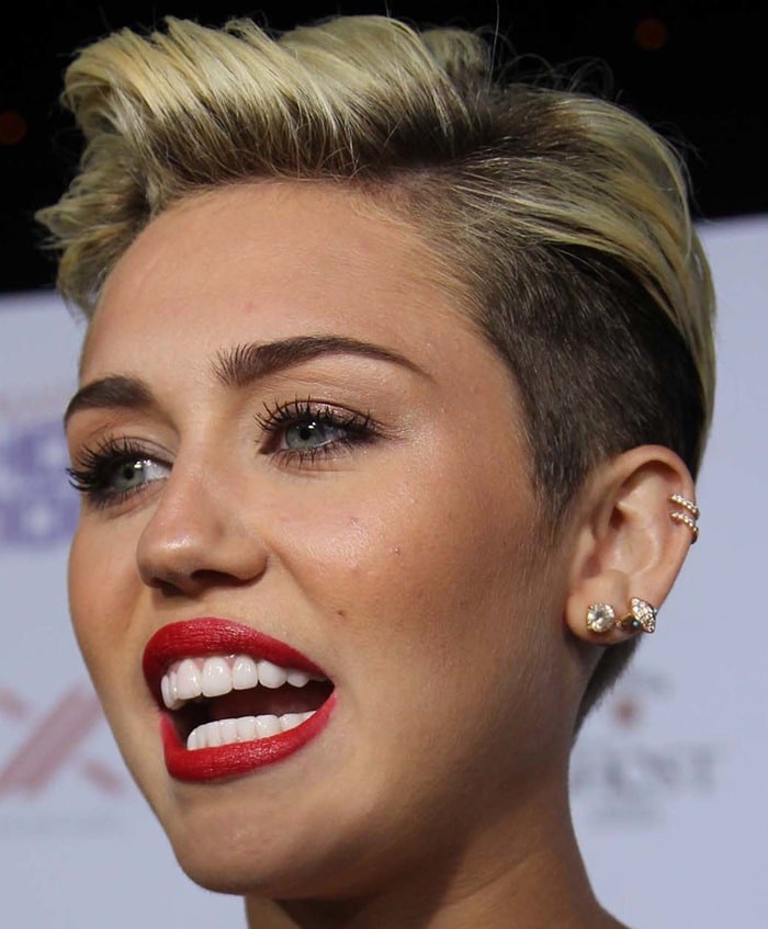 A close-up of Miley Cyrus at the Maxim 2013 Hot 100 Party held at Vanguard on May 15, 2013, in Hollywood, California, showcasing her iconic cropped blonde hairstyle, bold red lip, and radiant makeup