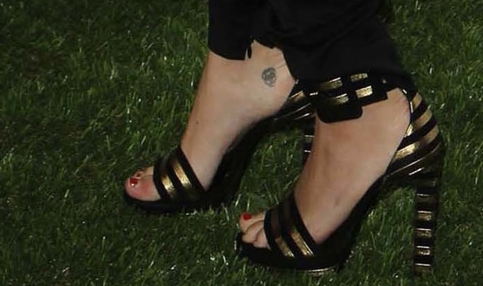 A closer look at Miley's gorgeous Saint Laurent 'Paloma' sandals, showcasing the striking black and gold striped design and high-platform heel