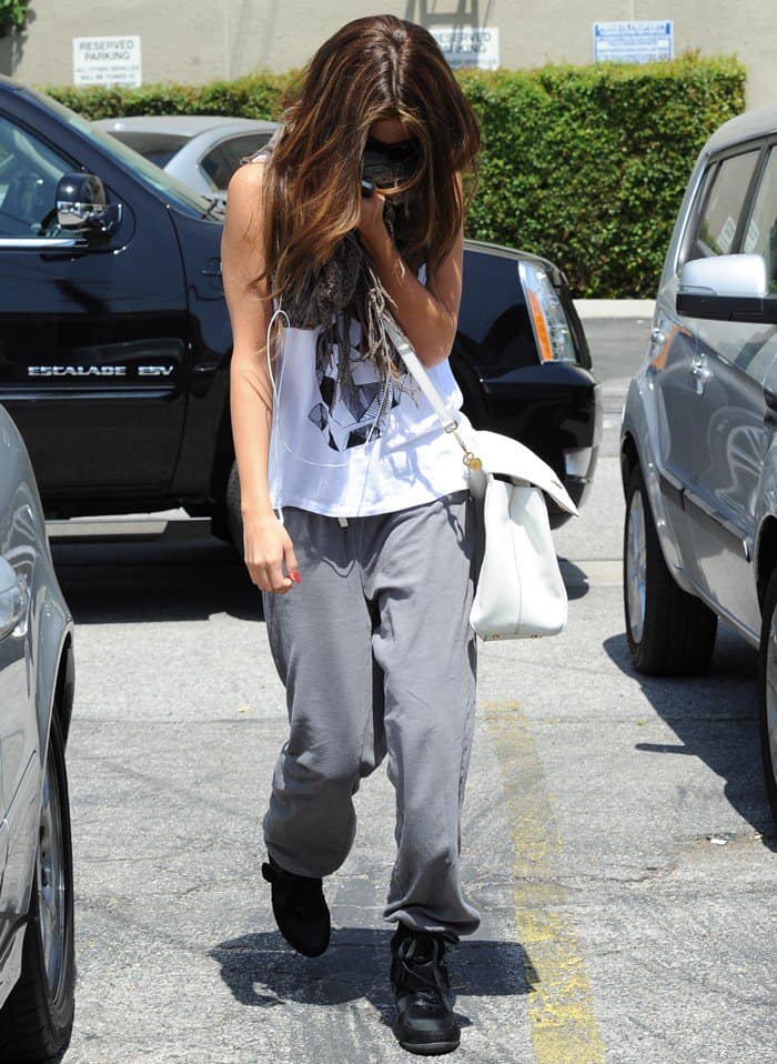 Selena Gomez was seen in Los Angeles wearing a Stylestalker Geo Bunny tee, paired with Top Moda Sammy 6 Velcro high top sneakers, accessorized with a Dolce Gabbana Miss Sicily bag in Bianco, and wrapped in a BDG Cooperative two-way scarf