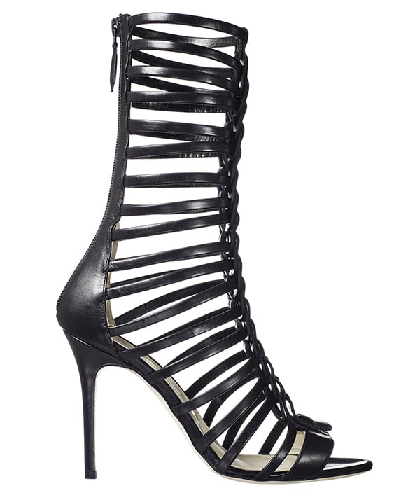Brian Atwood’s “Isabeli” gladiator sandals feature slim leather straps with sculpted T-bar detailing, a back zip for ease, and a towering stiletto heel that delivers graphic impact from every angle