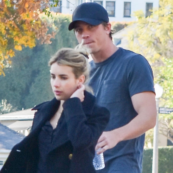 Emma Roberts walks alongside Garrett Hedlund in Los Angeles wearing a black coat over a dark top, with her hair pulled into a loose bun