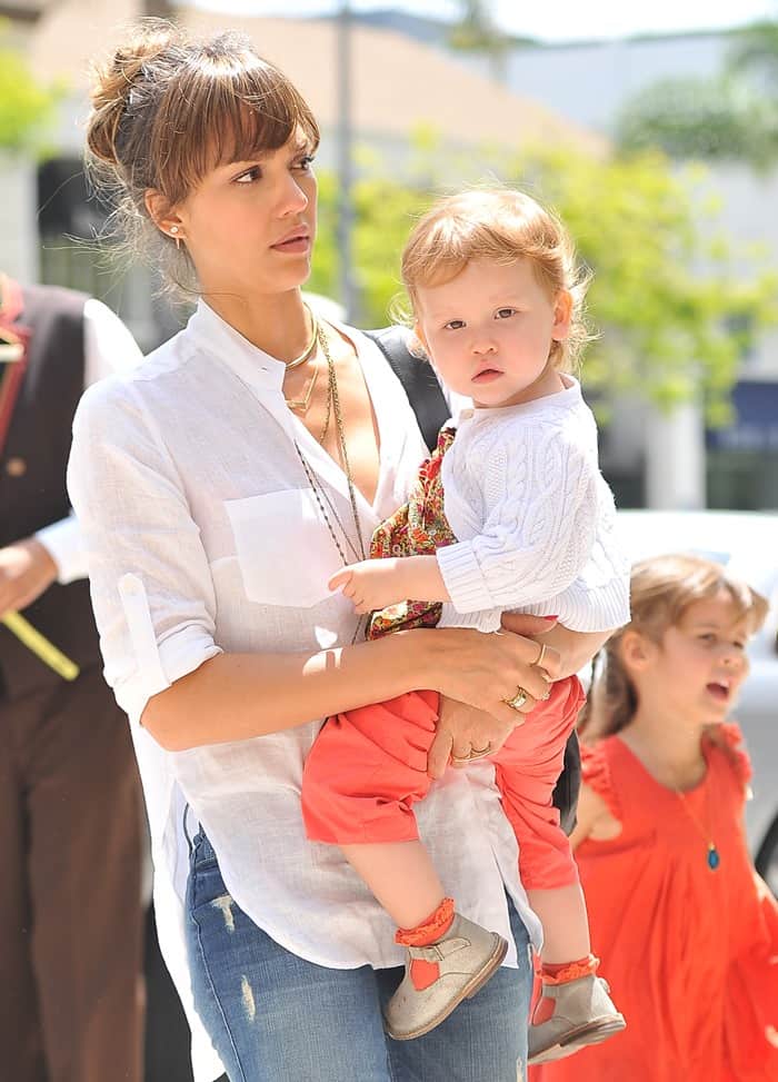 Jessica Alba carries her daughter, Haven Garner Warren, to lunch at Bouchon Bakery, pairing distressed skinny jeans with a breezy white blouse and layered gold jewelry for an effortlessly polished daytime look