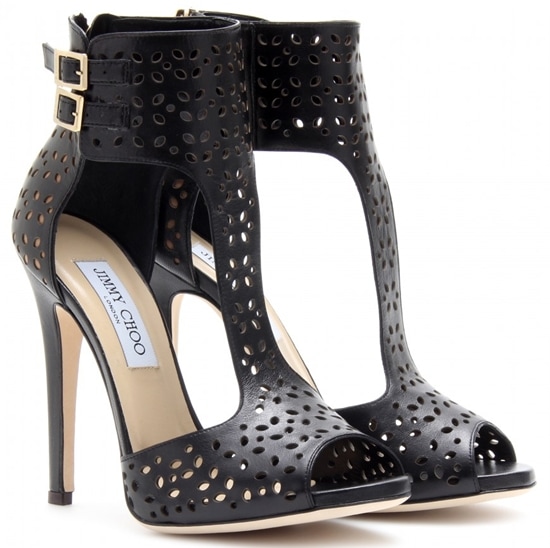 The black leather Jimmy Choo “Malika” booties offer a sleek, high-contrast look, with precise perforations and a sharp stiletto heel that anchors the edgy silhouette