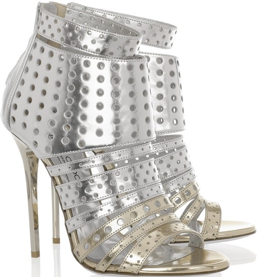 The silver Jimmy Choo “Malika” booties feature a high-shine metallic finish with dense perforation and layered straps that give the silhouette a bold, futuristic edge