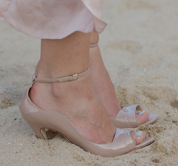 A close-up of Katharine McPhee’s nude patent leather heels sinking into the sand, highlighting the impractical choice of footwear for the beach setting at Lipton's Summer Tastes Party