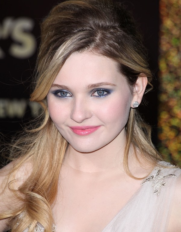 Abigail Breslin completed her red-carpet look with softly swept-back hair, smoky blue eye makeup, and sparkling stud earrings, adding a youthful glamour to her appearance at the Los Angeles premiere of New Year's Eve