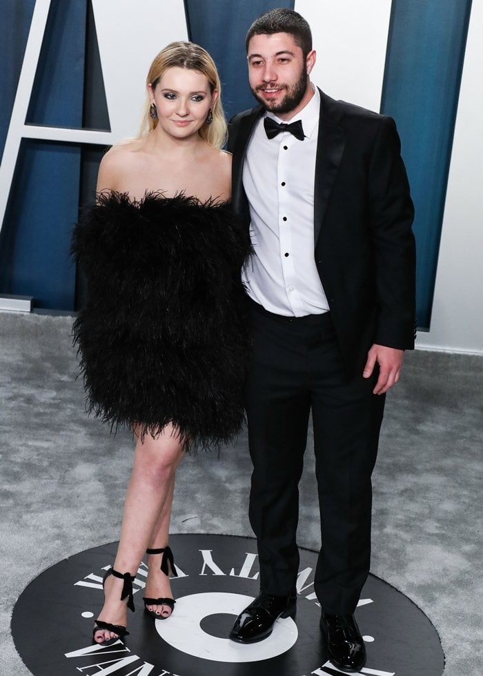 Abigail Breslin and her future husband, Ira Kunyansky, attend the 2020 Vanity Fair Oscar Party at the Wallis Annenberg Center for the Performing Arts in Beverly Hills, California, on February 9, 2020, with the actress wearing a strapless black feather mini dress by LOULOU and black ankle-tie sandals that balanced the look's dramatic texture with understated elegance