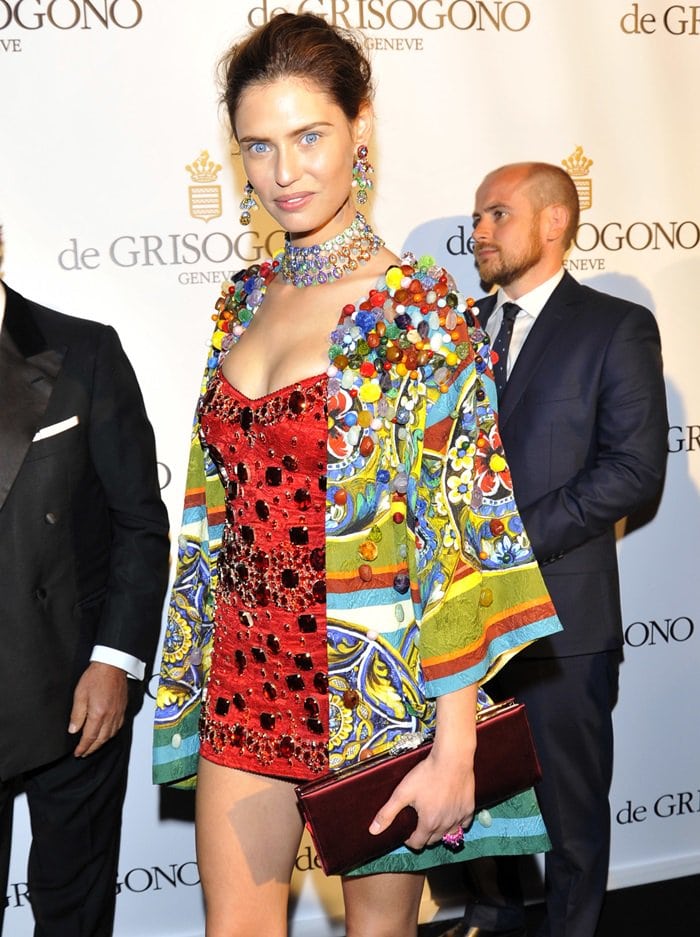 Bianca Balti in Cannes, enhancing her vibrant red dress with a lavish necklace, ornate earrings, and a richly decorated kimono, turning heads with her elaborate style