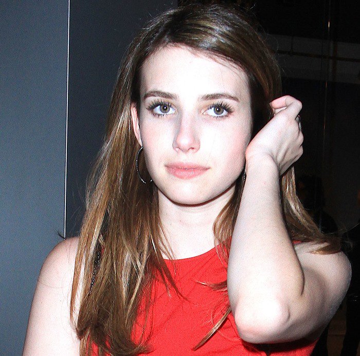 Emma Roberts shows off her soft, natural hairstyle and striking hazel eyes, complementing her bold red dress
