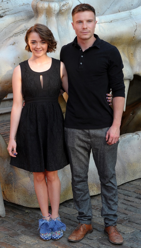 A huge dragon skull hulks behind Maisie Williams and co-star Joe Dempsie