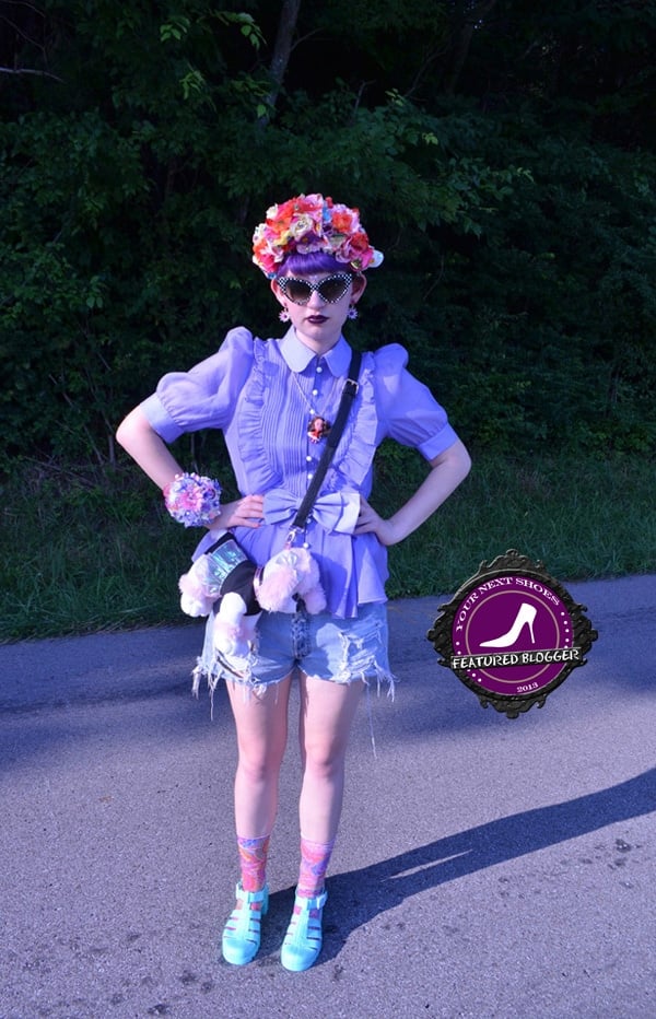 Zoe stuns in a whimsical lavender blouse, distressed denim shorts, pastel socks, and aqua jelly sandals, complete with a floral crown and statement accessories