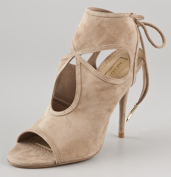 Aquazzura “Sexy Thing” booties in nude suede, defined by signature cutouts, an open toe, and delicate lace-up ties at the back—an instantly recognizable silhouette that combines sensual design with leg-lengthening elegance