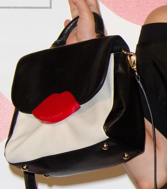 Close-up of Oona Chaplin's Lulu Guinness 'Audrey' bag, featuring a black-and-white colorblock design with the brand's signature red lips clasp for a playful pop of color