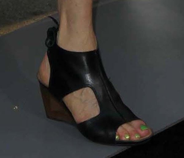 A close-up of Catherine Hardwicke's striking black leather open-toe sandal booties with green nail polish