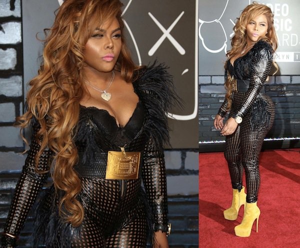 Lil Kim turned heads at the MTV Video Music Awards in a daring black mesh jumpsuit with feathered accents, cinched with a bold gold belt, and paired with eye-catching yellow Christian Louboutin “Daf Booty” ankle boots