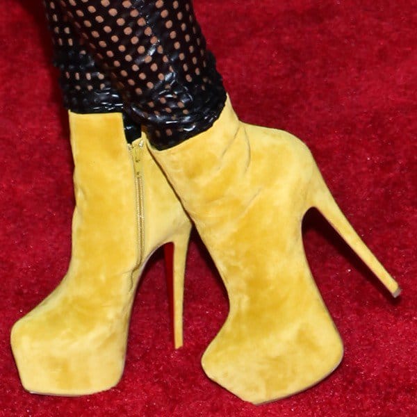 A close-up of Lil Kim’s bold yellow Christian Louboutin “Daf Booty” ankle boots featuring a towering platform and signature red sole