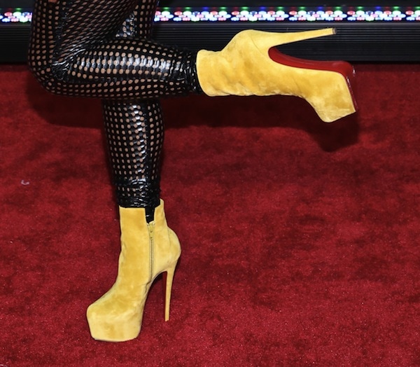 A close-up of Lil Kim’s bold yellow Christian Louboutin “Daf Booty” ankle boots featuring a towering platform and signature red sole