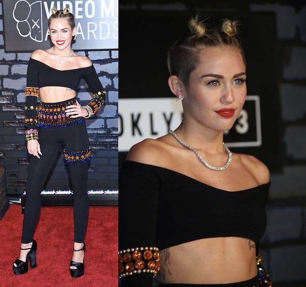 Miley Cyrus made a bold statement at the MTV VMAs with her off-the-shoulder crop top and high-waisted leggings adorned with colorful jewels, paired with platform heels and space buns for an edgy look