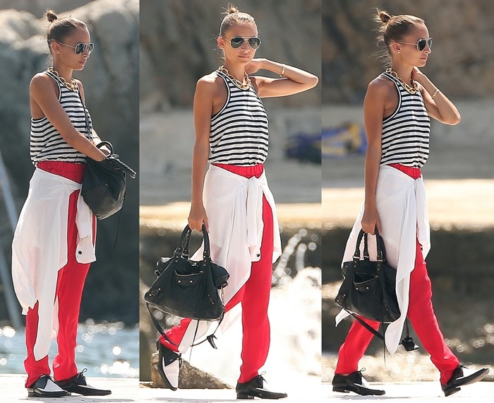 Nicole Richie’s effortlessly chic outfit in Cap D’Antibes, France, on July 27, 2013, featured a T by Alexander Wang linen silk blend striped tank top, red trousers, Saint Laurent perforated two-tone derby oxfords in Nero Black/Optique White, Ray-Ban 3025 aviator sunglasses in gold/green, and a classic Balenciaga City bag in black