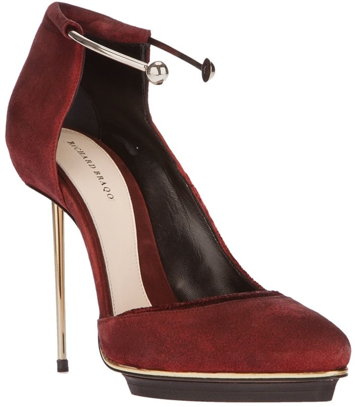 Richard Braqo’s red suede “Coralle” pumps feature a striking gold ankle bangle, metallic pin heel, and platform trim for a bold, sculptural finish