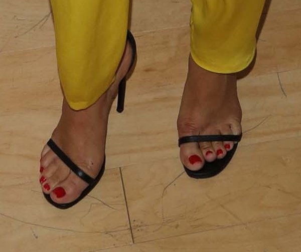 Ashley Madekwe’s black Saint Laurent “Jane” sandals deliver a sleek, minimalist finish that sharpens the bold impact of her yellow jumpsuit