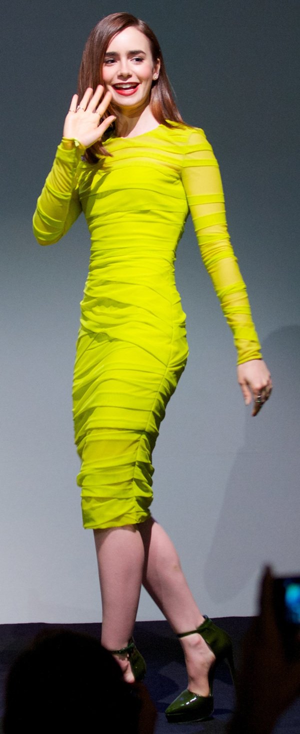 Lily Collins greets fans in a striking neon yellow ruched dress and matching green heels at a promotional event