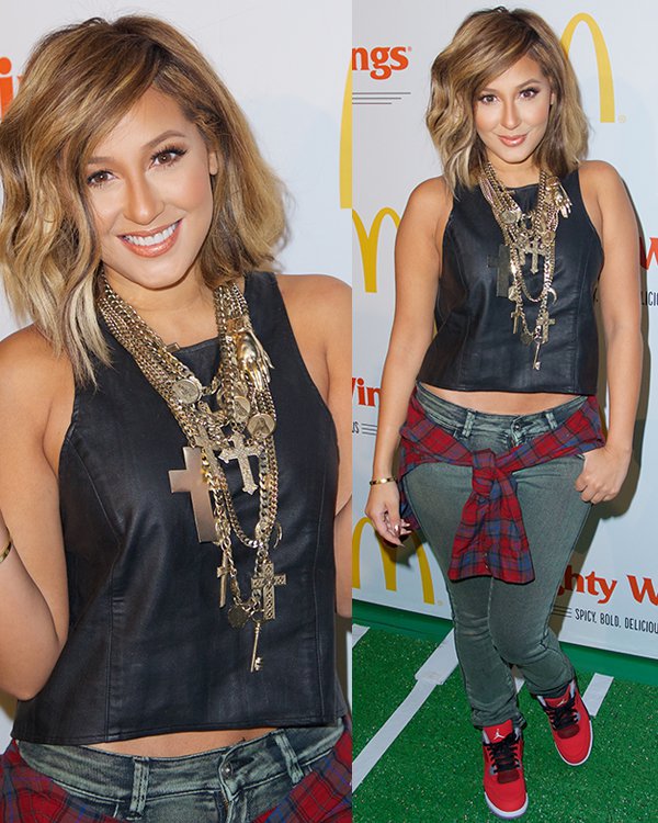 Adrienne Bailon styled her cropped leather top and plaid shirt with red-and-black Air Jordan sneakers, adding a sporty punch to her layered green-carpet ensemble