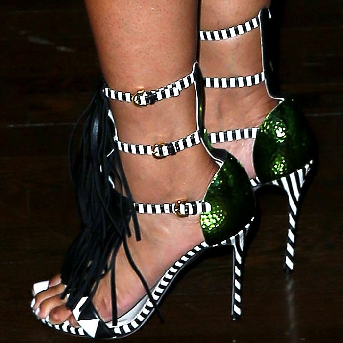 Ashanti steps out in bold Sergio Rossi "Tawaraya" sandals featuring striking black-and-white stripes, metallic green heel counters, and layered fringe details